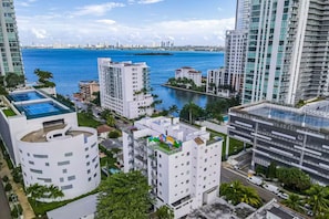 Un hotel moderno con piscina en la azotea, un puerto deportivo al fondo y vistas del horizonte urbano.