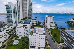 A high-rise building complex with multiple floors, a waterfront view, and a road with vehicles.
