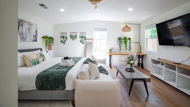 Une chambre à coucher moderne, équipée d’un lit, d’un bureau, d’une chaise, d’un téléviseur et d’un ventilateur de plafond.