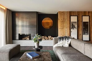 Ein modernes Wohnzimmer mit Kamin, einer Couch, einem Couchtisch und einer wandmontierten, runden Leuchte.