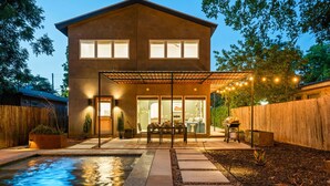 A modern house with a swimming pool, patio, and string lights. - Casa Tranquila • Pool, Ping Pong, Game Room & More (Austin)