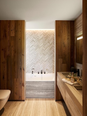Ein modernes Badezimmer mit einem Holzbadschränken, einer freistehenden Badewanne und einer Wand mit Fischgrätmuster.