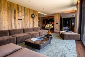 Ein modernes Wohnzimmer mit einer Holzwand, einer Sofagarnitur, einem Couchtisch und einer Vase mit Blumen.