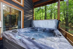 Ein Whirlpool in einer Gartenanlage mit einer Holzterrasse und Blick auf einen Wald.