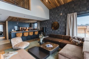 A modern interior with a bar area, seating, and a view through a large window. - View village, parking, ski locker, 220m², Megève (Megève)