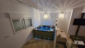 Un espace bien-être comprenant un jacuzzi, un canapé et un téléviseur.