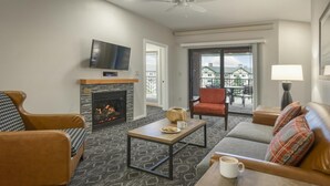 Una sala de estar con chimenea, televisor, sofá, mesa de centro y balcón con vistas.