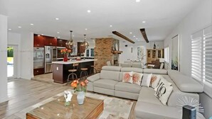 A spacious living area with a large sofa, a coffee table, and a kitchen in the background.