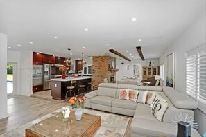 A spacious living area with a large sofa, a coffee table, and a kitchen in the background.