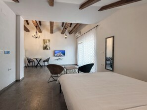 A hotel room with a bed, a desk, two chairs, a TV, and a large mirror. - Seaside Village apartments (Herceg Novi)