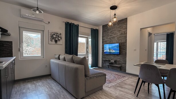 A modern living room with a sofa, TV, dining area, and kitchen. - Seaside Village apartments (Herceg Novi)