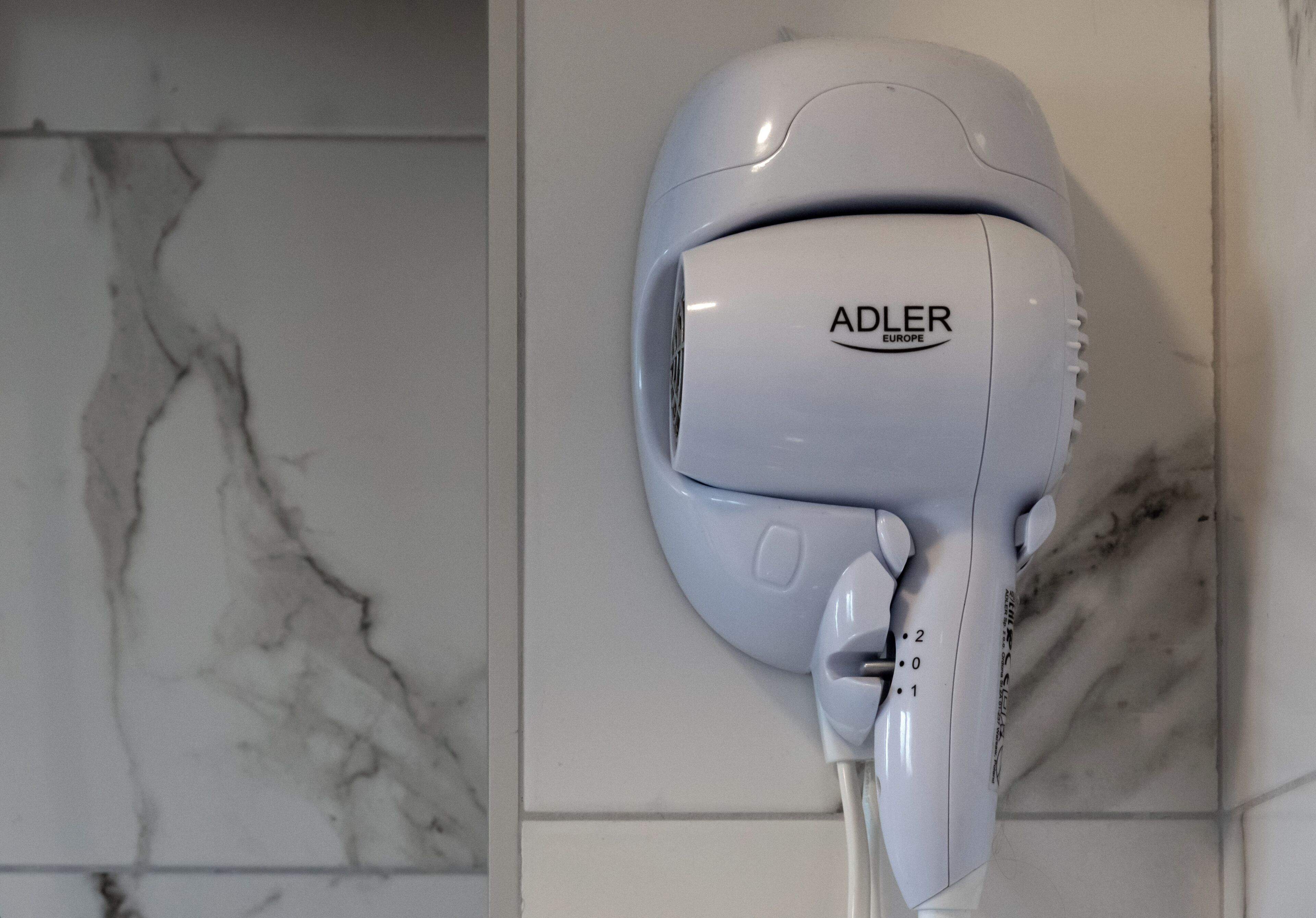 A hair dryer mounted on a wall with a marble pattern.