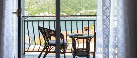 A balcony with wicker furniture, a table, and a glass of drink.