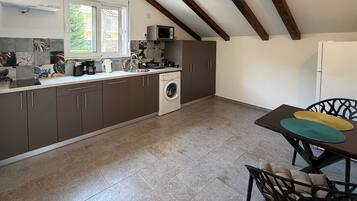 A kitchen with a washing machine, a microwave, and a dining area with a table and chairs.