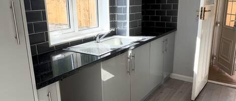 A kitchen with a sink, cabinets, and a window.