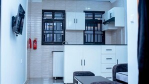 A modern kitchen with white cabinets, black-framed windows, and a built-in oven. - Martin aviator hotel (Kigali)