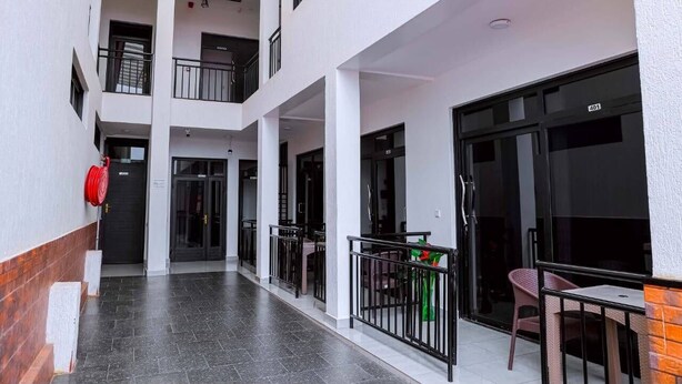 A multi-level building with balconies, a fire extinguisher, and a table with chairs. - Martin aviator hotel (Kigali)