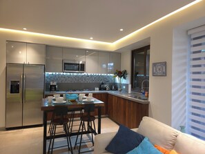 A modern kitchen with stainless steel appliances, a central island, and a dining area with bar stools. - Heart of Zona Romantica. Modern 1BR/2BA Oasis-Steps away to everything (Puerto Vallarta)