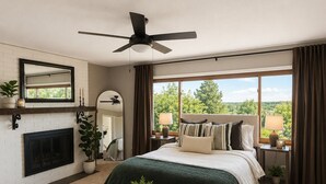 Ein Schlafzimmer mit einem großen Bett, einem Kamin, einem Deckenventilator und Blick ins Freie.