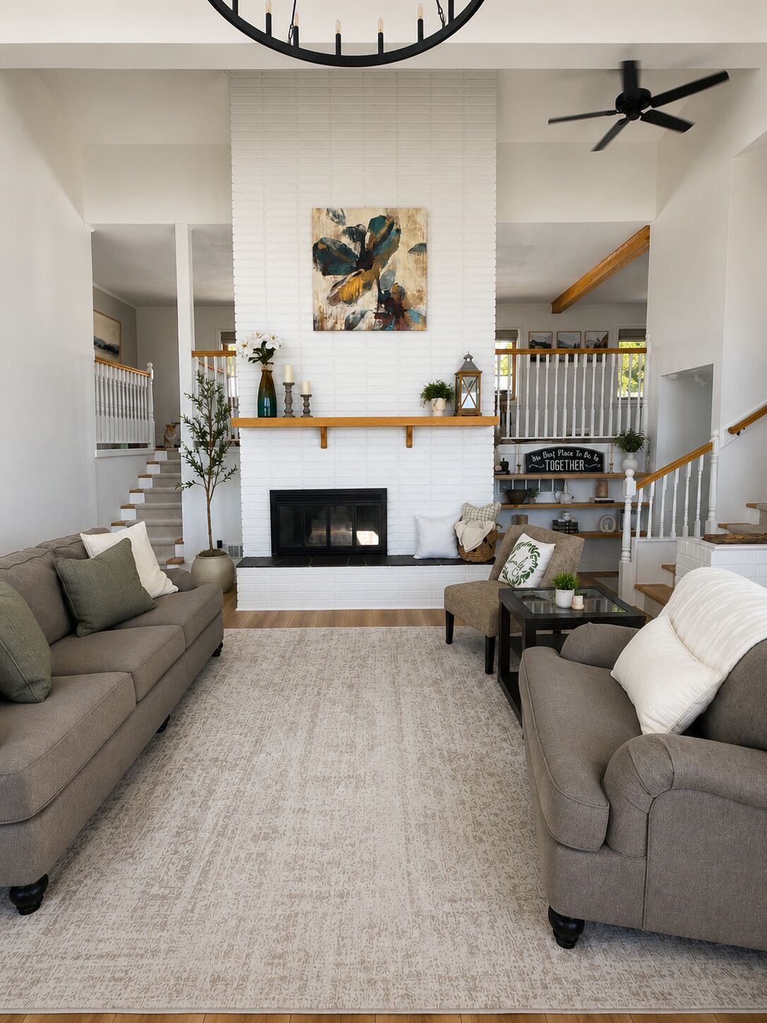 Un salon avec une cheminée, deux canapés, une table basse et un escalier doté d’une rampe.