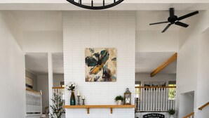 Ein Wohnzimmer mit Kamin, zwei Sofas, einem Couchtisch und einer Treppe mit Geländer.