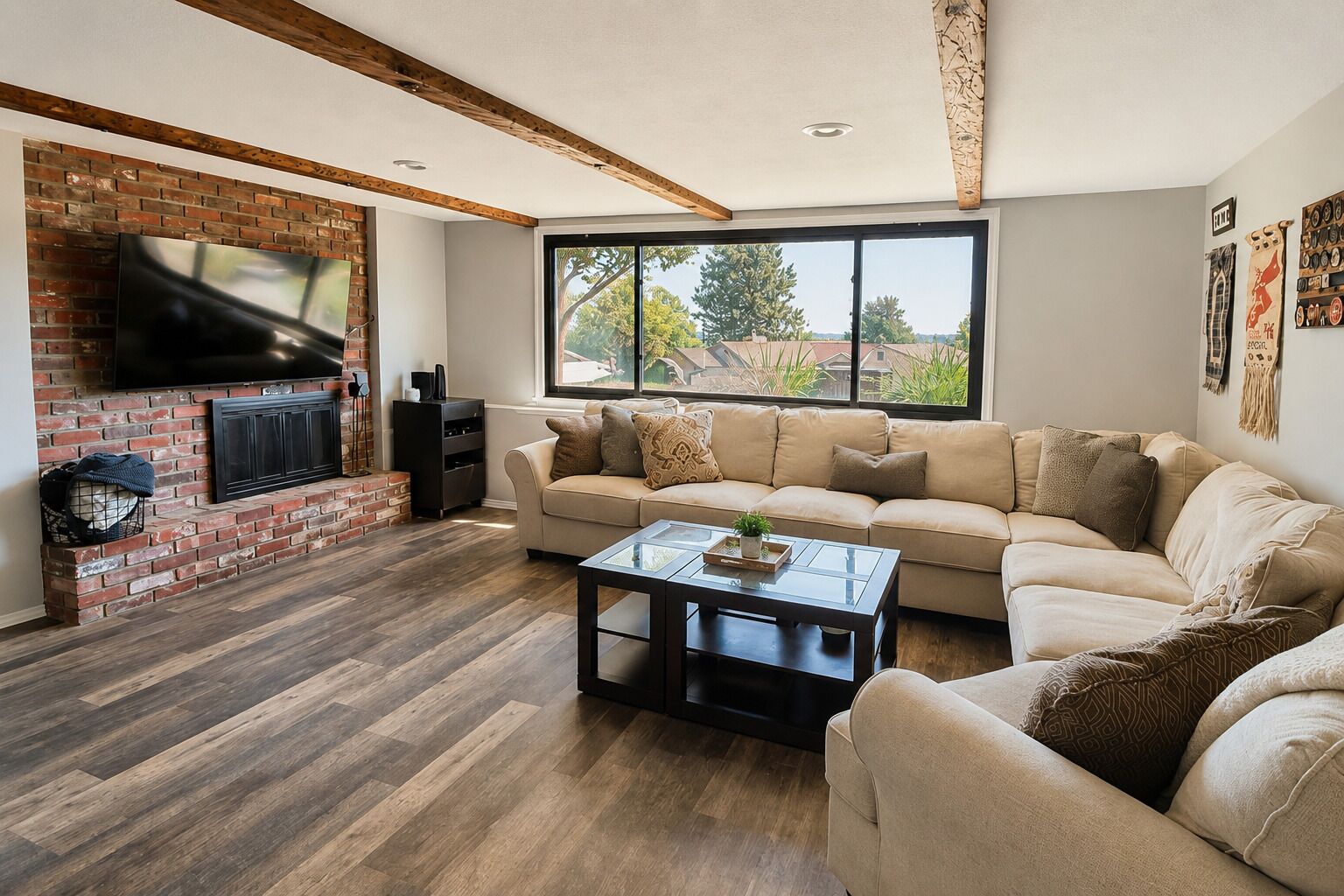 A living room with a brick fireplace, a sofa, a coffee table, and a large window.
