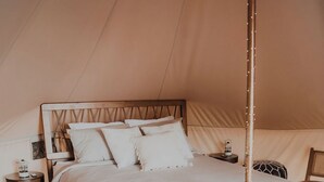 Ein Zeltraum mit Bett, Nachttischen und einer Hängelampe.