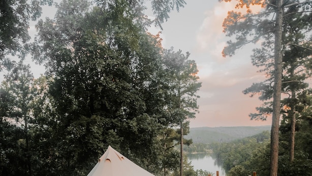 Ein Zelt auf einer Holzterrasse mit Blick auf einen See und Wald.