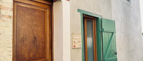 A building with a wooden door, green shutters, and a mailbox.