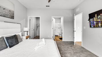 A modern hotel room with a large bed, a nightstand, a wall-mounted lamp, and a cityscape painting.