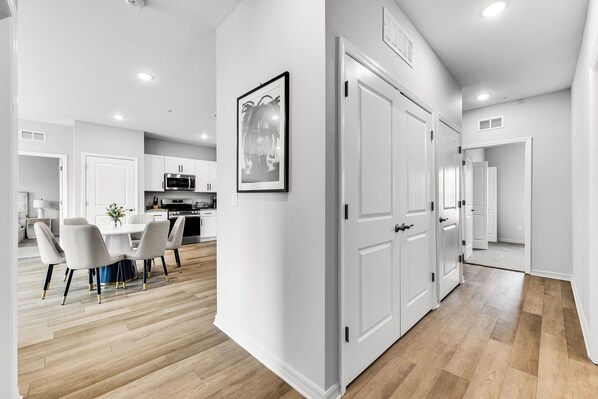 A modern kitchen with white cabinets, a microwave, and a dining area with a white table and chairs. - Shire Village (Ocala)