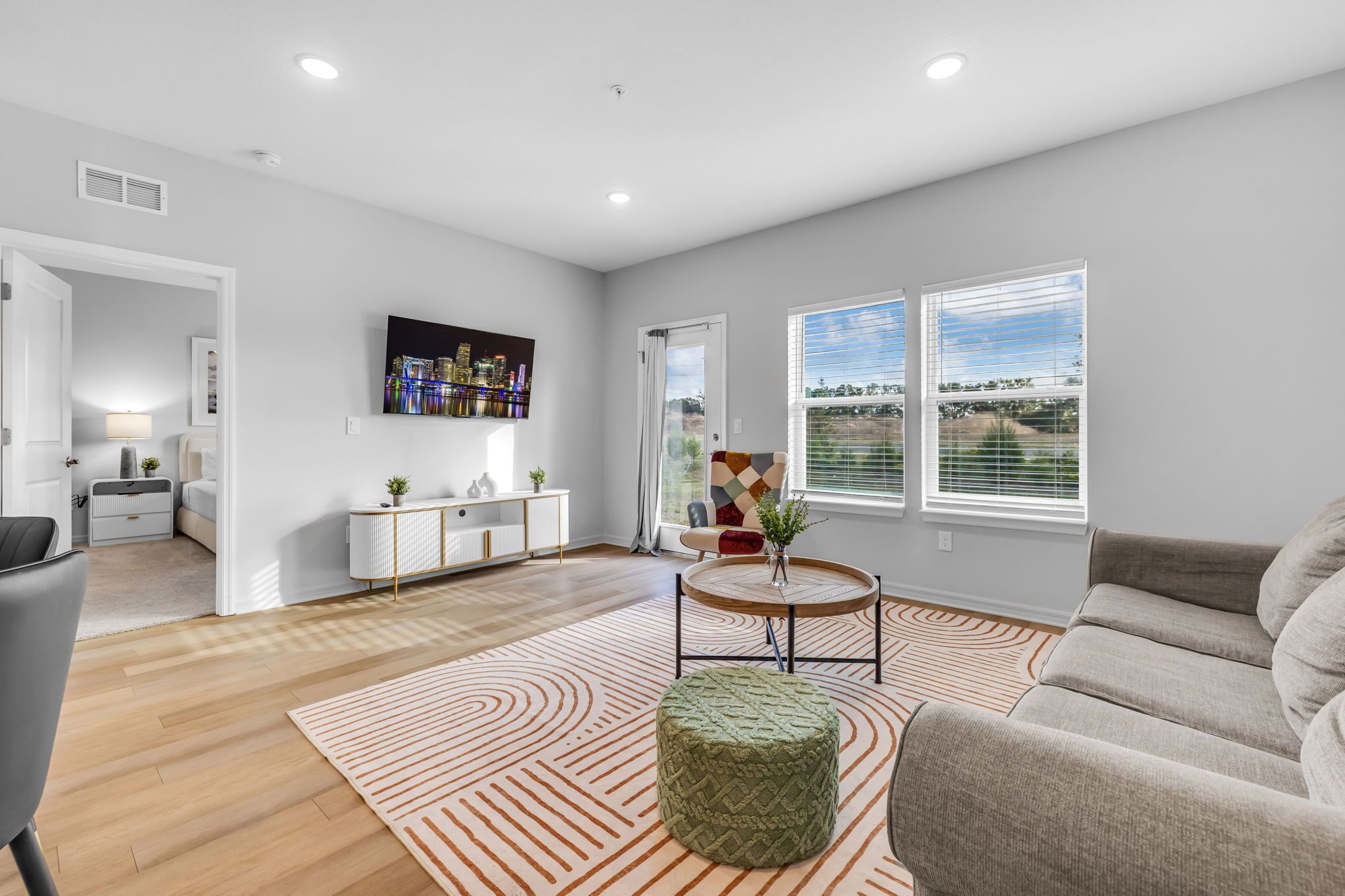 A modern living room with a sofa, a coffee table, and a TV mounted on the wall.