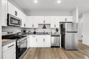 A modern kitchen with white cabinets, stainless steel appliances, and a granite countertop.