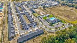 An aerial view of a residential area with multiple houses, roads, and a swimming pool.