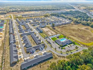 An aerial view of a residential area with multiple houses, roads, and a swimming pool.