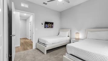 Un dormitorio con cama, mesita de noche, ventilador de techo y un cuadro en la pared.