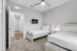 A bedroom with a bed, bedside table, nightstand, ceiling fan, and a painting on the wall. - Shire Village (Ocala)