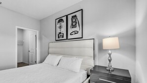 A bedroom with a bed, a nightstand with a lamp, and two framed pictures on the wall.