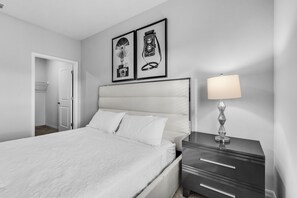 A bedroom with a bed, a nightstand with a lamp, and two framed pictures on the wall.