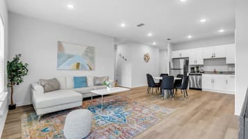 Una sala de estar moderna con un sofá blanco, una mesita de centro y un tapete colorido.
