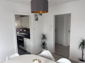 A modern kitchen with white cabinets, a black countertop, and a grey pendant light.