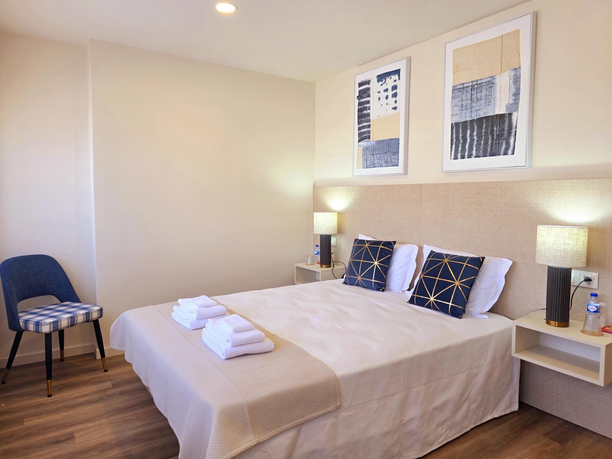 Ein Hotelzimmer mit Bett, Sessel, Nachttisch und Wandbild.