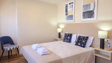 Ein Hotelzimmer mit Bett, Sessel, Nachttisch und Wandbild.