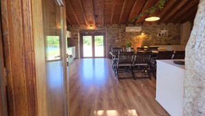 A rustic interior with wooden beams, stone walls, and a dining area with tables and chairs. - Casa Rio D'Além | Eco-sustainable | Swimming pool | River | Pure Nature (Parada do Monte e Cubalhão)