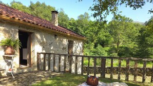 A stone building with a tiled roof, a wooden fence, and a picnic setup on the grass. - Casa Rio D'Além | Eco-sustainable | Swimming pool | River | Pure Nature (Parada do Monte e Cubalhão)