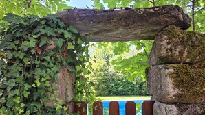 A wooden gate with a blue sign, surrounded by greenery and a stone structure. - Villa Vetusta | Rustic | Pool | Northern Portugal (PENSO)