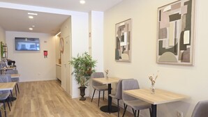 A modern dining area with wooden flooring, grey upholstered chairs, and a potted plant. - Ponto Norte | Room 2 | Town Centre | Melgaço | The Northernmost Town in Portugal (Melgaço)