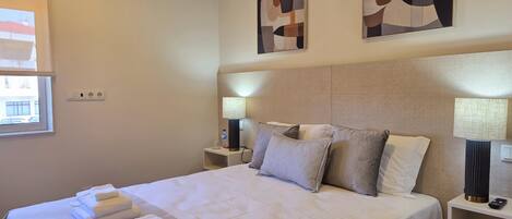 A hotel room with a bed, two bedside lamps, a nightstand, and abstract wall art.