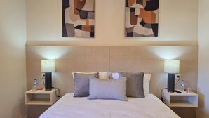 A hotel room with a large bed, two bedside tables, two wall-mounted lamps, and abstract artwork above the bed. - Ponto Norte | Room 2 | Town Centre | Melgaço | The Northernmost Town in Portugal (Melgaço)