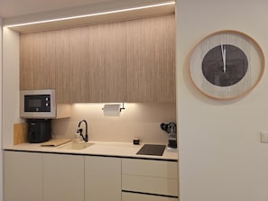 Una cocina moderna con microondas integrado, cafetera y un lavamanos con grifo.